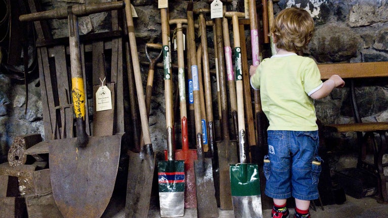 A close-up of a child looking at garden tools at Patterson's Spade Mill